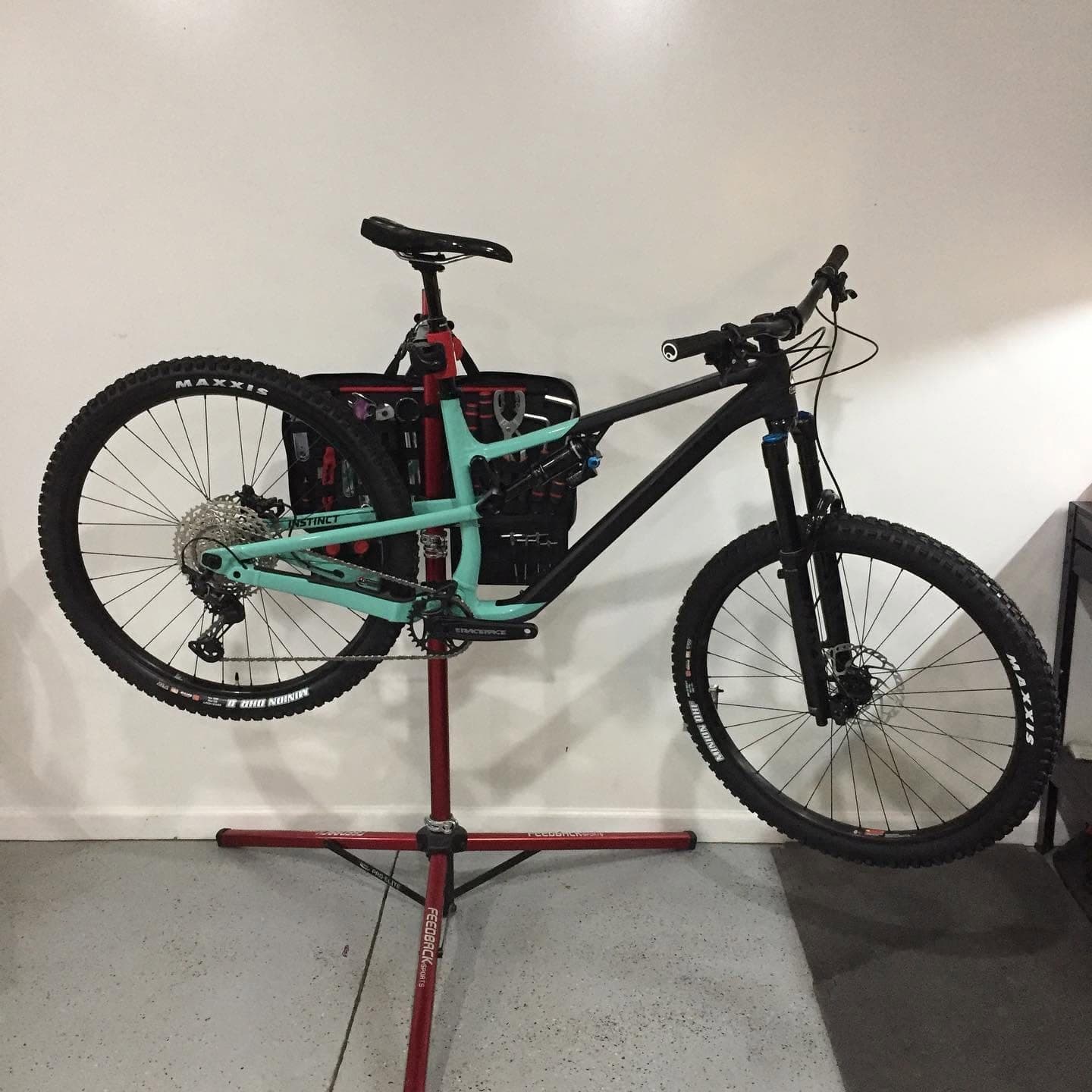Black and teal full-suspension mountain bike clamped in a repair stand